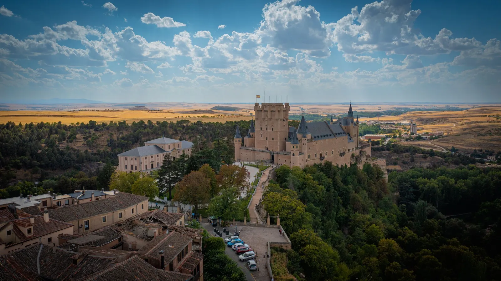 Der Alcázar von Segovia über den Bäumen, dahinter die weite kastilische Hochebene