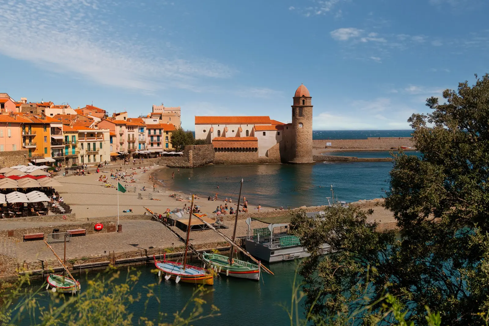 Collioure in Südfrankreich: Strand, bunte Häuser, Fischerboote und der Glockenturm der Kirche am Meer