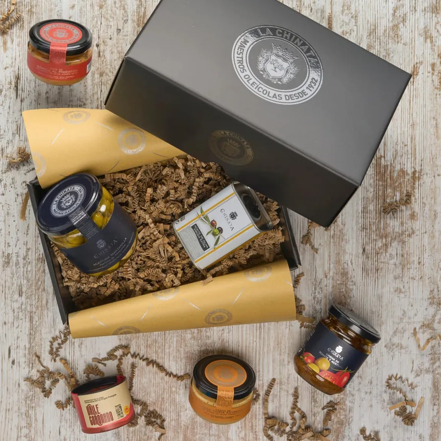 Geöffnete schwarze Geschenkbox von La Chinata mit Pimentón-Dose, Olivenöl-Dose, Oliven, Käsecreme und Pasteten