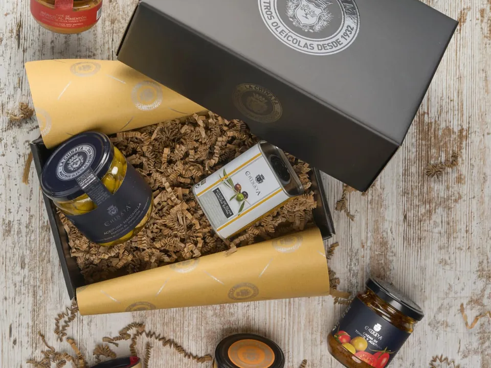Geöffnete schwarze Geschenkbox von La Chinata mit Pimentón-Dose, Olivenöl-Dose, Oliven, Käsecreme und Pasteten