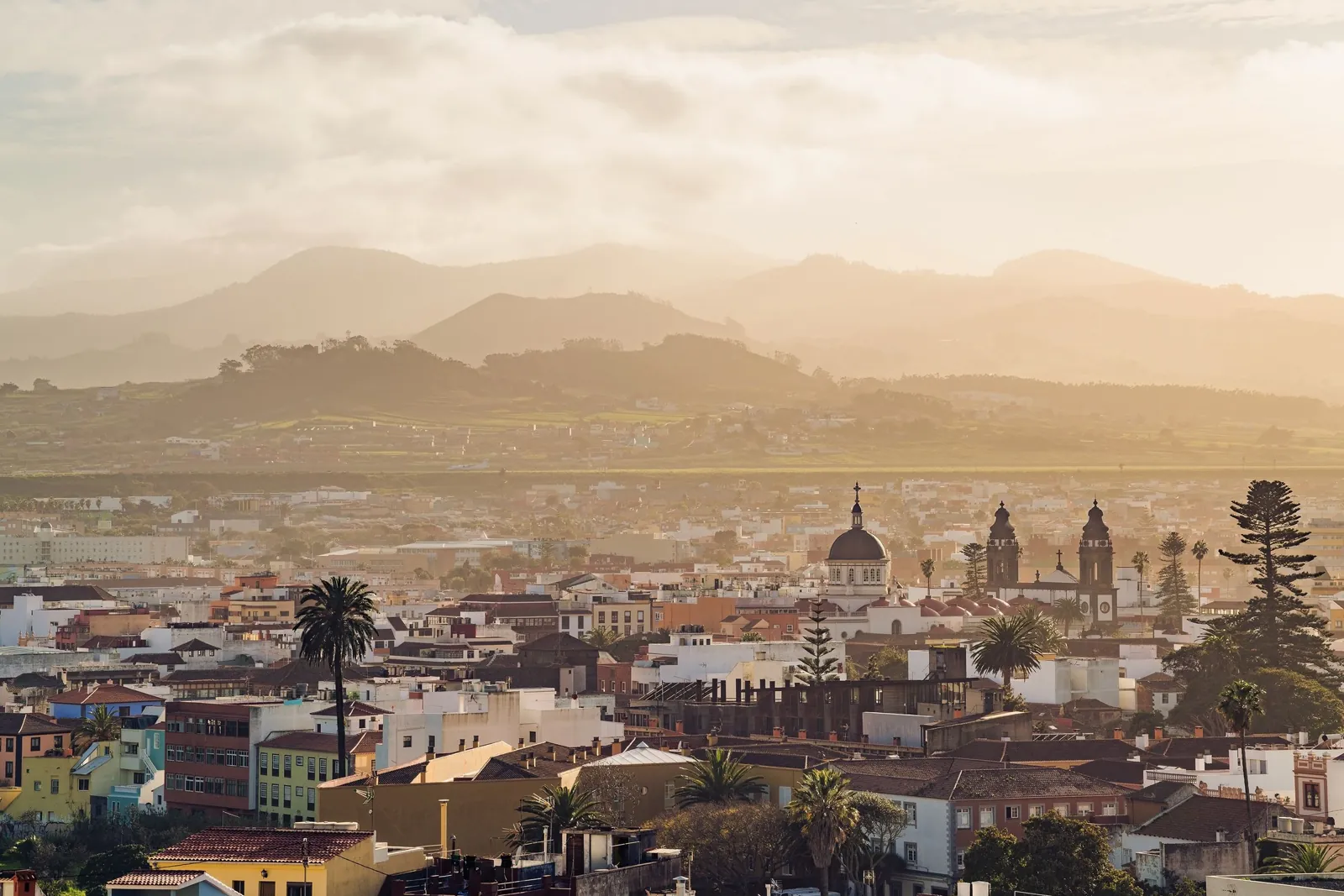 Blick über die Altstadt von San Cristóbal de La Laguna mit Kirchtürmen und Bergen im goldenen Abendlicht