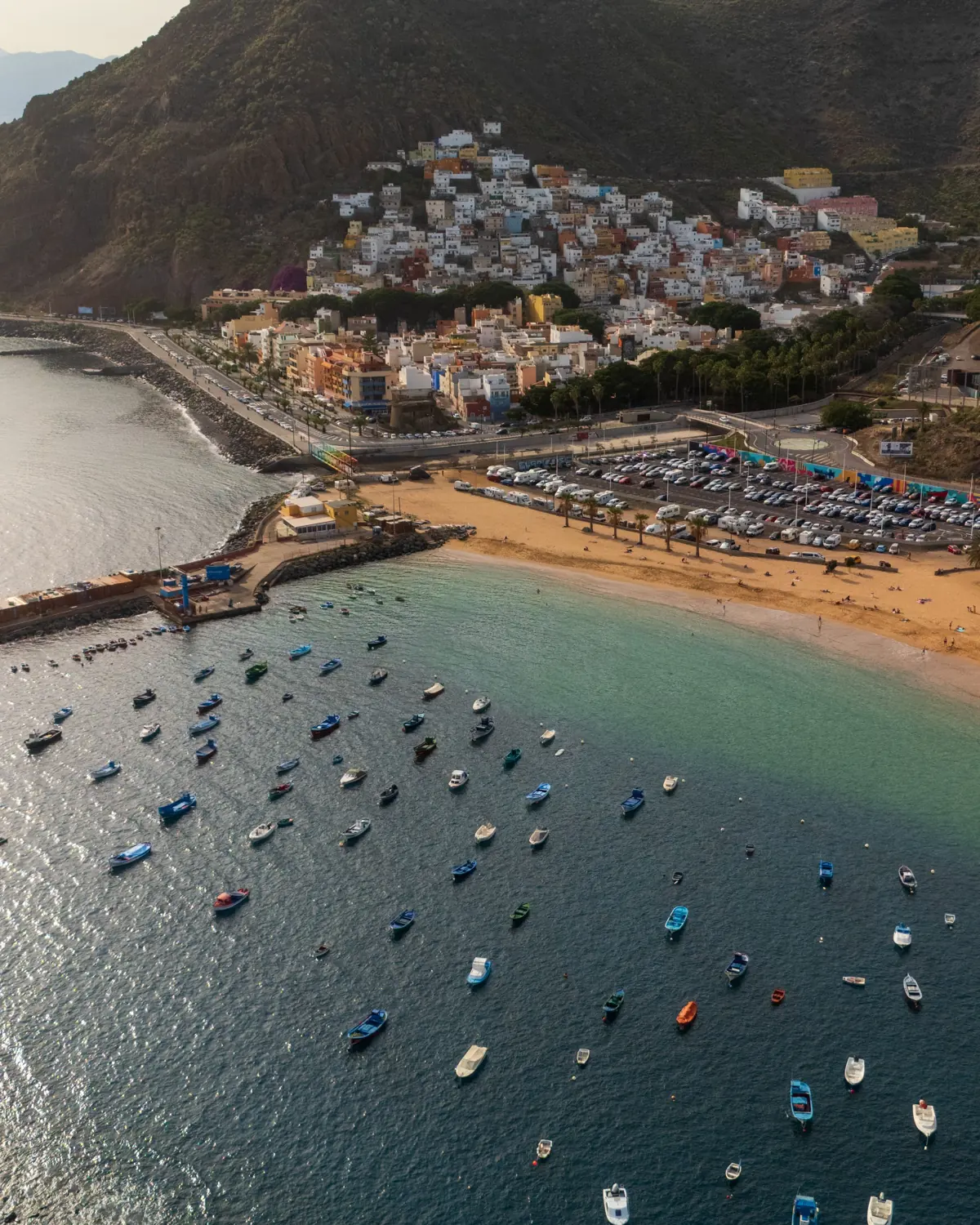Fischerboote vor San Andrés, dahinter die bunten Häuser des Dorfes am Hang und der Rand der Playa de Las Teresitas