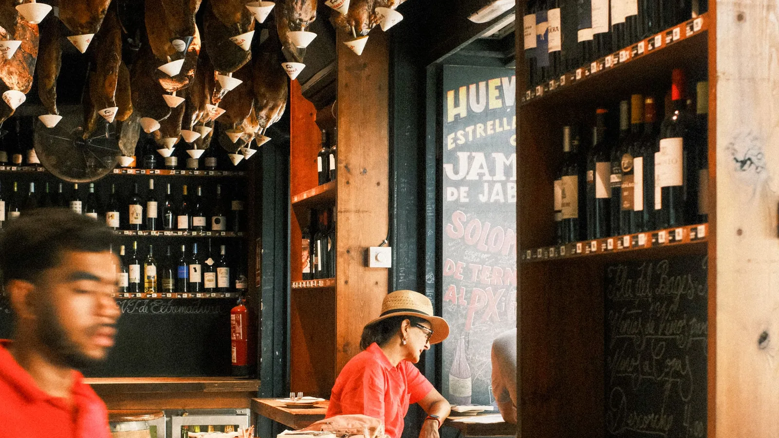 Tapasbar in Barcelona mit Schinken an der Decke und einer Kreidetafel, auf der Jamón angeboten wird