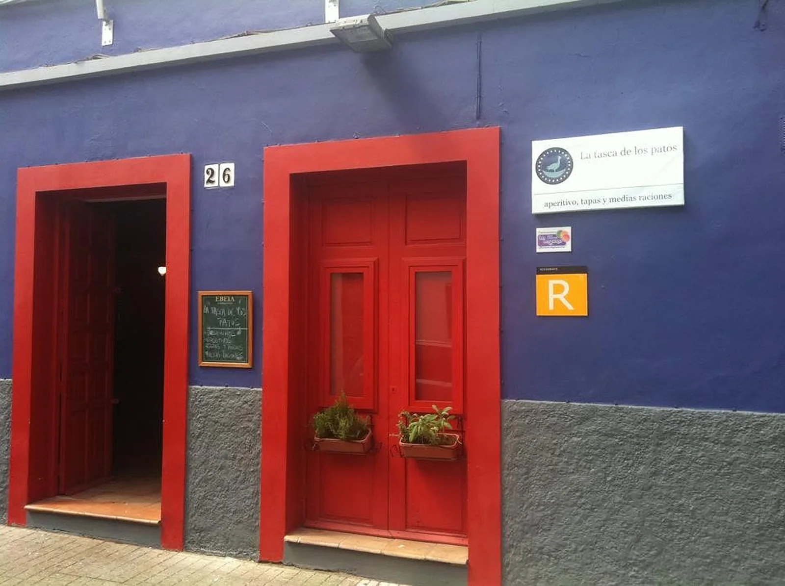 Eingang der Tasca de los Patos in La Laguna: rote Holztüren an einer blauen Fassade