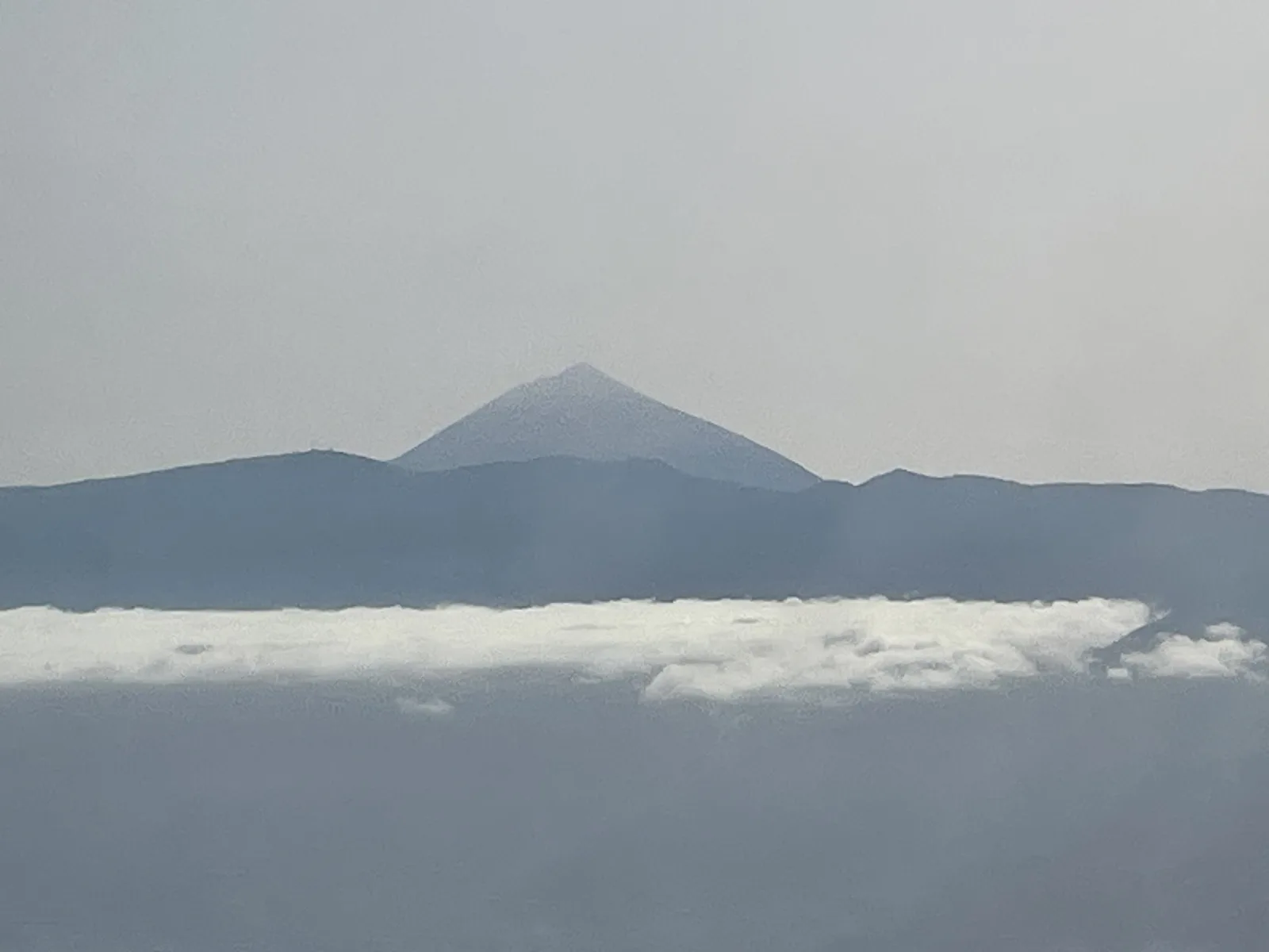 Der Teide ragt aus den Wolken, fotografiert aus dem Flugzeugfenster beim Anflug auf Teneriffa